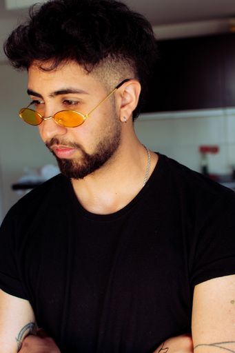 A portrait of a young Hispanic man wearing yellow sunglasses
