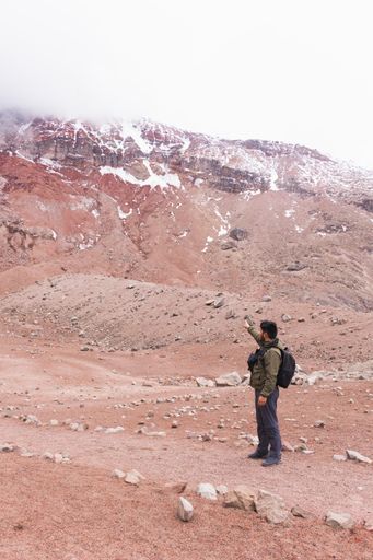 A vertical shot of the young man in the mountains, enjoying the fresh air and beautiful view.