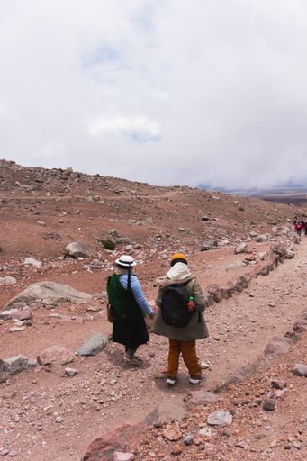 A vertical shot of the indigenous woman with a young traveler in the mountains. Ecuador, the Andes.