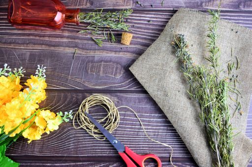 A top view of rosemary branches, flowers, and scissors on a rustic wooden table