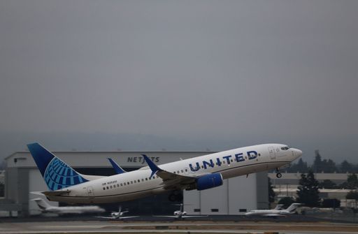 United Airlines Boeing 737-800 takes off from San Jose International Airport toward Denver, with the NetJets hangar in the background.
