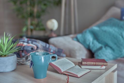 A closeup shot of a blue teacup and books on the wooden table