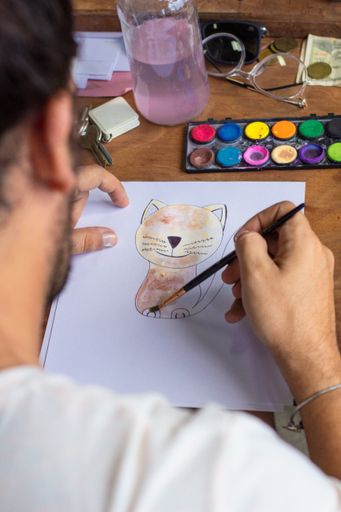 A man painting a cat at home