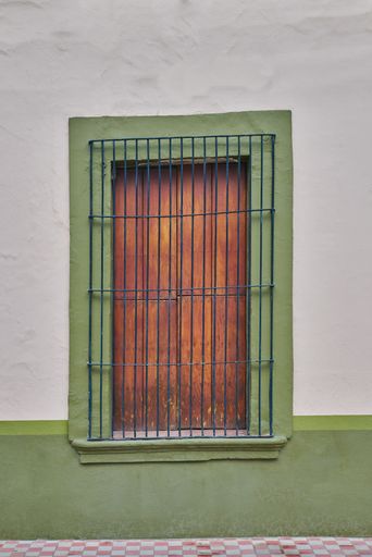 Rustic green colored facade with an antique wooden village window