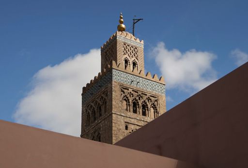 The Koutoubia Mosque tower in Marrakech, Morocco, stands tall against a clear blue sky, showcasing intricate architectural details.