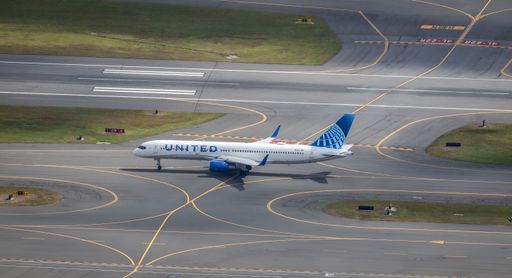 A United Airlines plane taxiing on a sunny airport runway, showcasing aviation and travel themes.