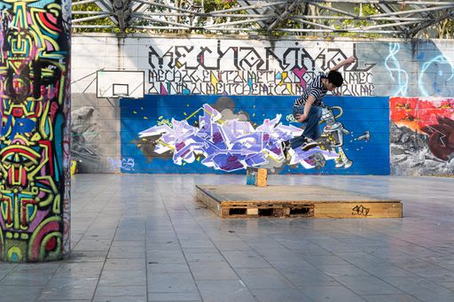 The skateboarders doing tricks in a skate park with bright graffiti in Udine, Italy