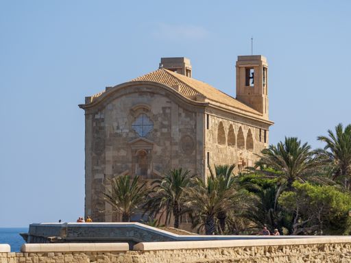 A beautiful view of the church of  San Pedro y San Pablo in Tabarca, Spain with palm trees
