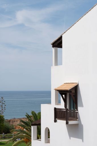 A vertical shot of a white wall with a balcony and a view at the sea in a tropical environment