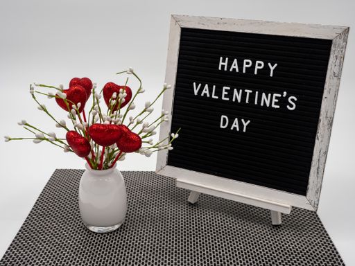 A closeup shot of "Happy Valentine's Day" text on a black frame with decorations on the side