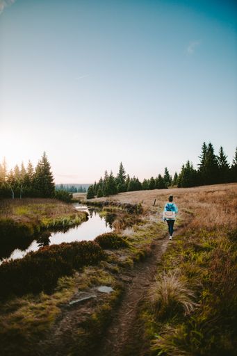 A vertical shot of a girl in rural landscape with a stream in Jizerka village in Czech Republic