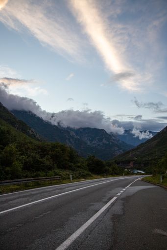 A vertical shot of a highway surrounded by mountains and forests
