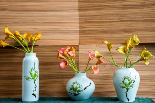 A beautiful image of three flowers in their different shaped pots against a wooden background