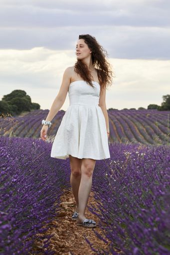 A vertical shot of a beautiful young woman in the lavender field.