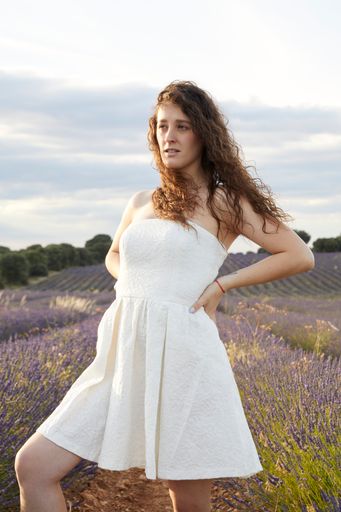 A vertical shot of a beautiful young woman in the lavender field.