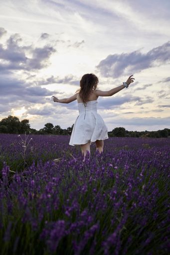 A vertical shot of a beautiful young woman in the lavender field.