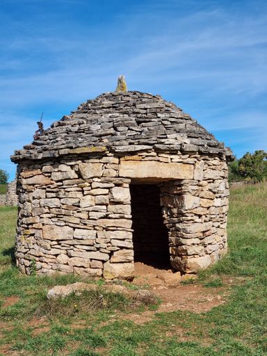 A vertical closeup of a small hut made of rocks in the field