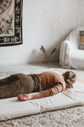 An adult tired woman lying on a yoga mat on the floor at home