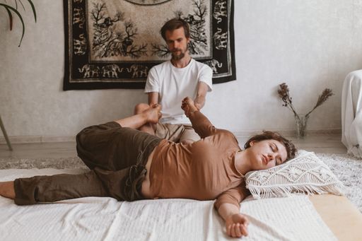 An adult Russian couple doing Thai yoga massage exercises on a mat at home