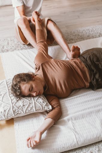An adult Russian couple doing Thai yoga massage exercises on a mat at home