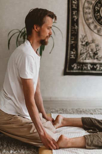 An adult Russian couple doing Thai yoga massage exercises on a mat at home