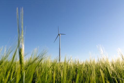 A closeup shot of a wind turbine in the field with beautiful green grass