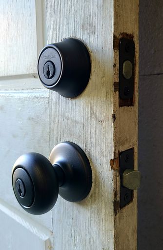 A vertical shot of a wooden door handle with a lock