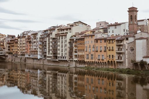 The buildings near the medieval stone arch bridge of Ponte Vecchio reflected in the Arno River in Florence