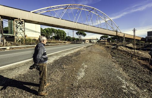 An old male standing on the road near a construction area under the sunlight in Spain