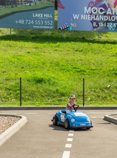A young child driving in a small electric car on a track of an attraction in the Malta park.