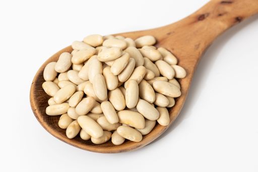 Close-up of a wooden spoon with raw cannellini beans isolated on a white background.