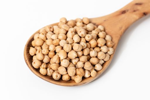 Wooden spoon with raw kabuli chickpeas isolated on a white background.