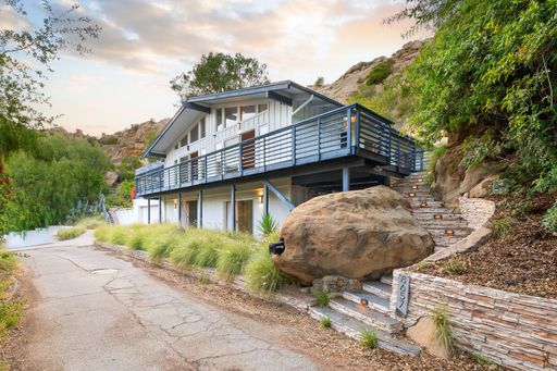 Modern luxury home featuring oversized windows, designer decor, spacious bedrooms, and sweeping views of the surrounding hills.