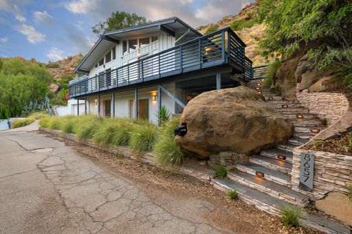 Modern luxury home featuring oversized windows, designer decor, spacious bedrooms, and sweeping views of the surrounding hills.
