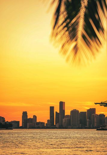 A beautiful view of a city near the sea during the sunset with yellow and orange colors