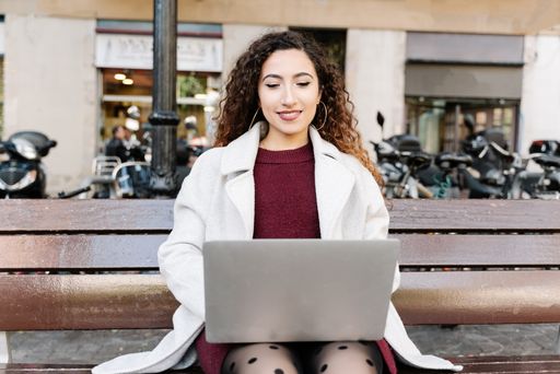 A beautiful female sitting on the bench while using her laptop