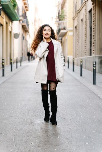 A vertical shot of an attractive female standing in the middle of buildings