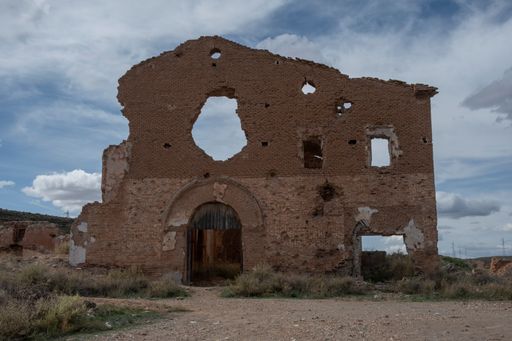 An old shattered building with an arched entrance against a cloudy sky in Belchite, Spain