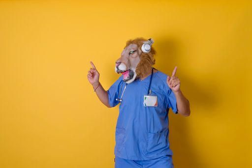 Doctor with stethoscope pointing fingers up and headphones on. Yellow background.