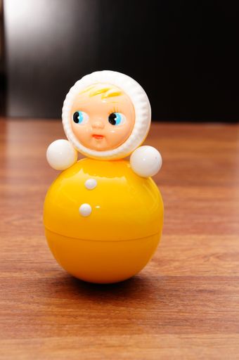A vertical shot of a plastic doll in white and yellow colors on the wooden table