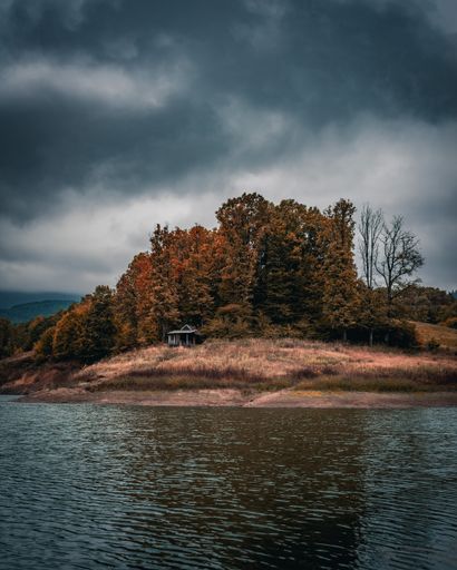A vertical shot of a beautiful island surrounded by lush greenery under dark clouds