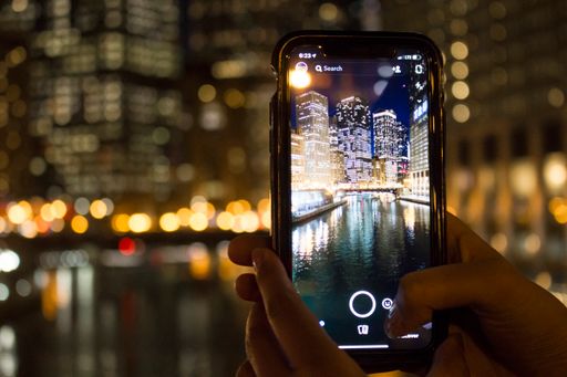 A person who is taking a photo of an amazing Chicago city at night time.
