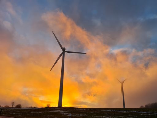 A beautiful scene of wind energy turbines under an orange sky at sunset
