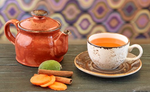 Teapot with organic tea and ginger with cut carrots and whole lime