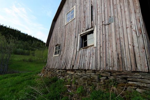 A tilted wooden barn, weathered and bowed with time. Captured in early evening light, showcasing the textures and character of forgotten Nordic crafts