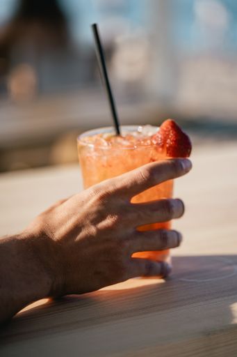 A vertical shot of a hand holding cocktail glass with strawberry