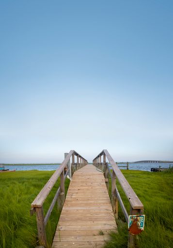 A vertical shot of a boat dock and waterfront with blue sky background