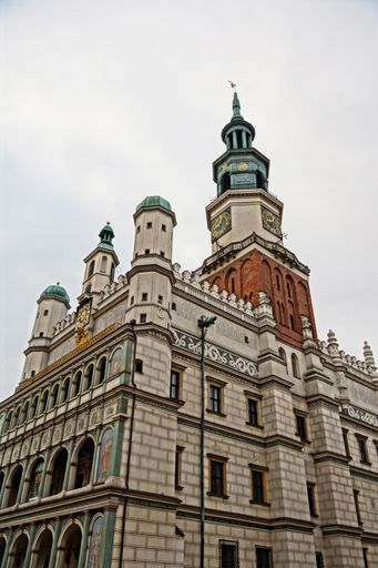 A low angle shot of the city hall with a tower of the old market under the cloudy sky