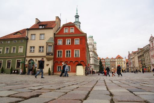 Poznan, Poland, a low angle shot of the city hall and the colored houses of the old market with walking people