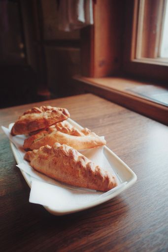 A vertical closeup shot of kibinais from Lithuanian cuisine on a white glassy tray on a wooden table